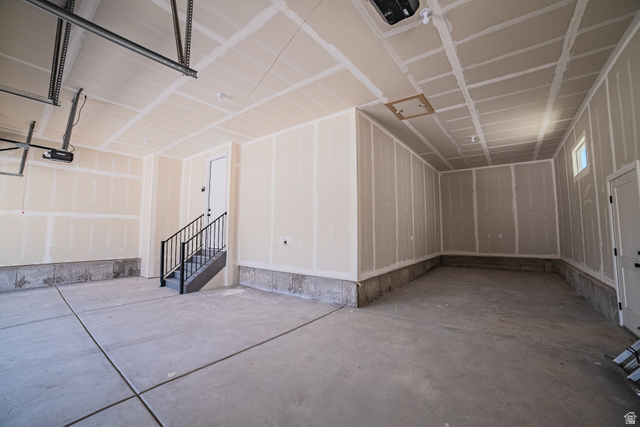 45 North Scarlet Maple Road, Unit 4317 Vineyard, UT 84059 - Photo 5 of 35 Spacious two-car garage featuring a concrete floor, high ceilings, and a staircase with black metal railings