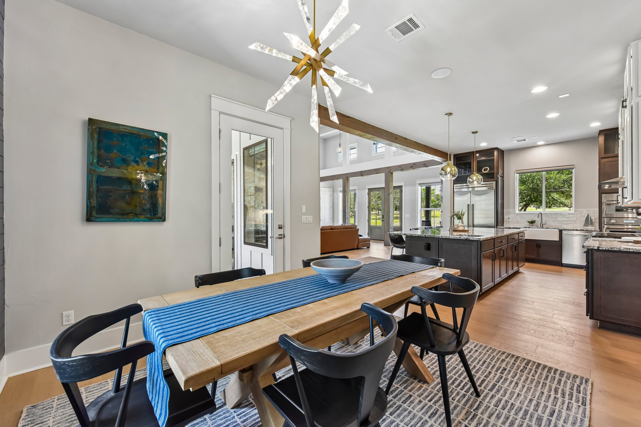 2203 Improver Road Spicewood, TX 78669 - Photo 5 of 38 Natural light floods this inviting dining space, featuring a modern chandelier and an open view to the kitchen.