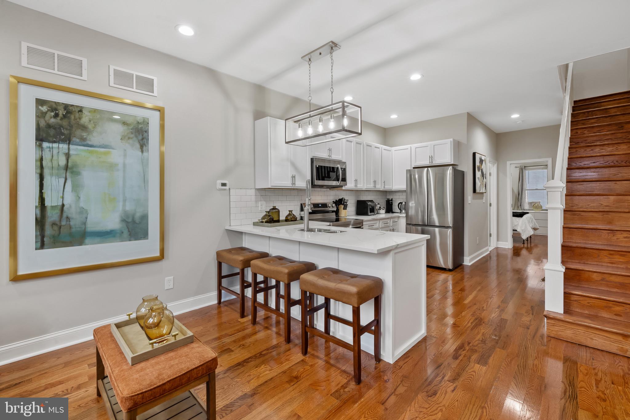 a kitchen with stainless steel appliances granite countertop a refrigerator a stove top oven and a dining table with wooden floor