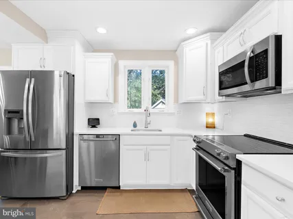 a kitchen with white cabinets and stainless steel appliances