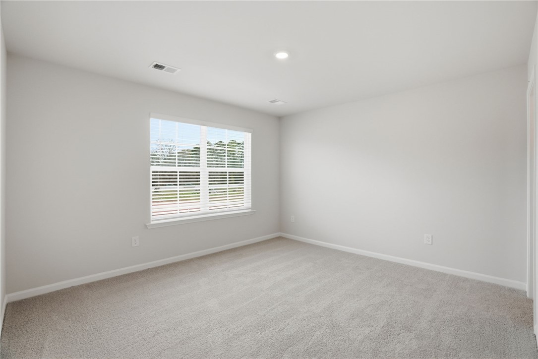 305 Lilac Loop Greenwood, SC 29646 - Photo 18 of 25 A well-lit bedroom with soft carpeting and large windows offering exterior views.