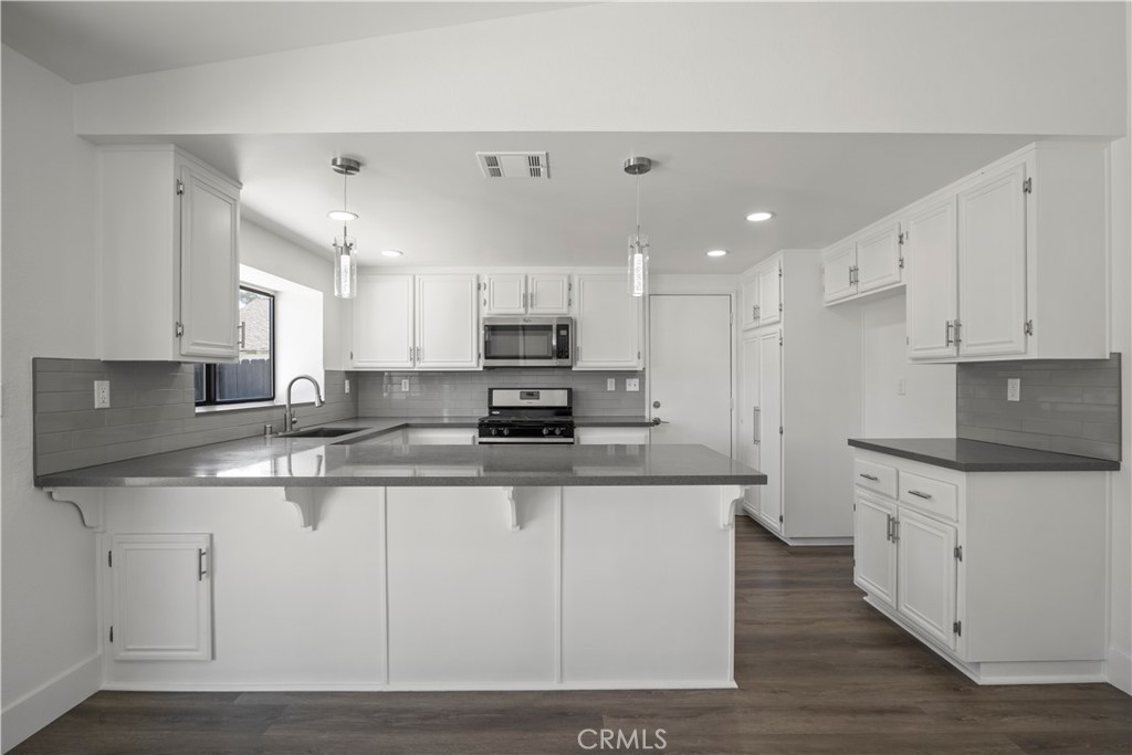 4225 Saddleback Road Palmdale, CA 93552 - Photo 24 of 61 a kitchen with stainless steel appliances granite countertop a stove top oven a sink a refrigerator and white cabinets
