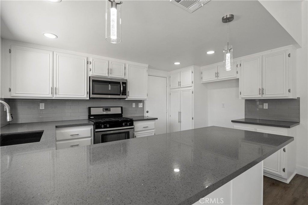4225 Saddleback Road Palmdale, CA 93552 - Photo 27 of 61 a kitchen with stainless steel appliances granite countertop a sink a stove top oven a counter space and cabinets