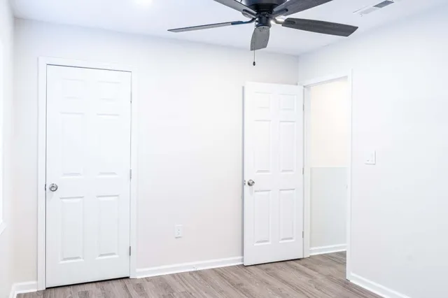 an empty room with wooden floor ceiling fan