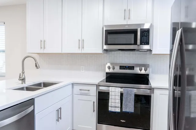 a kitchen with stainless steel appliances granite countertop a sink stove and microwave