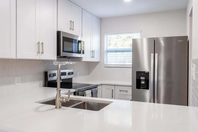 a kitchen with stainless steel appliances granite countertop a refrigerator sink and stove