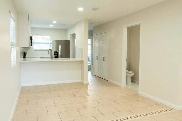 a view of kitchen with stainless steel appliances cabinets and empty shelves
