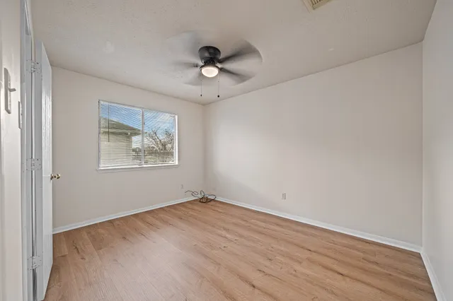 an empty room with wooden floor and windows