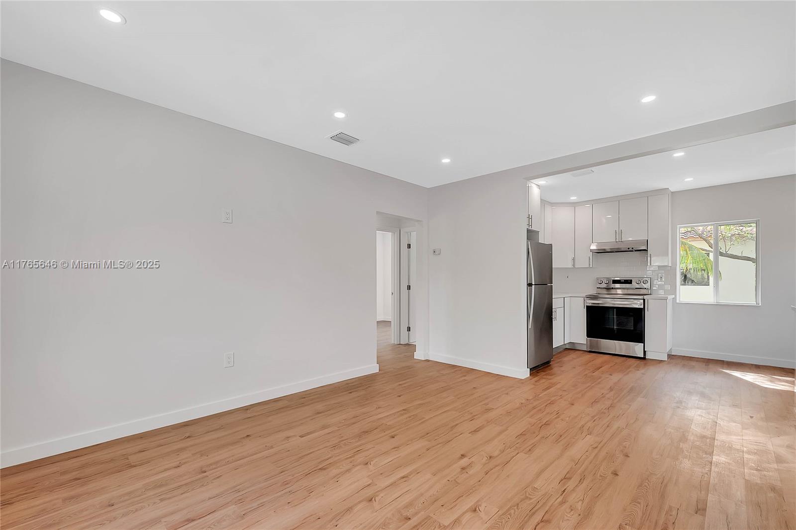 a view of a livingroom with a fireplace a ceiling fan and windows