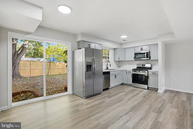 a kitchen with granite countertop a refrigerator oven a sink dishwasher a stove and a refrigerator with wooden floor