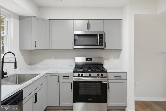 a kitchen with cabinets stainless steel appliances a sink and a stove