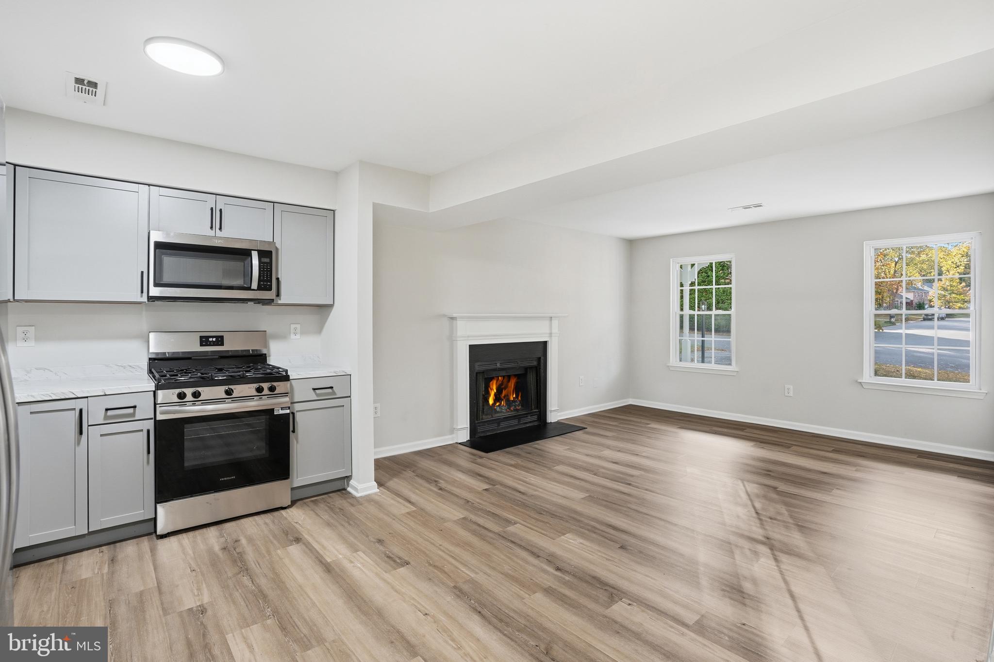 13357 Pelican Road Woodbridge, VA 22193 - Photo 21 of 48 a view of kitchen with granite countertop a stove top oven a sink with dishwasher and a fireplace with wooden floor
