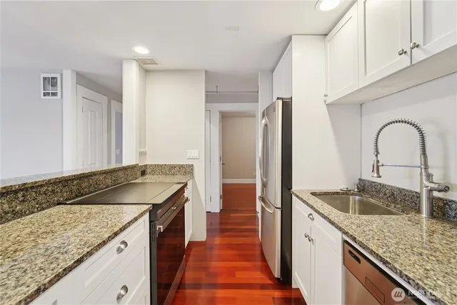 a kitchen with granite countertop a sink and a refrigerator
