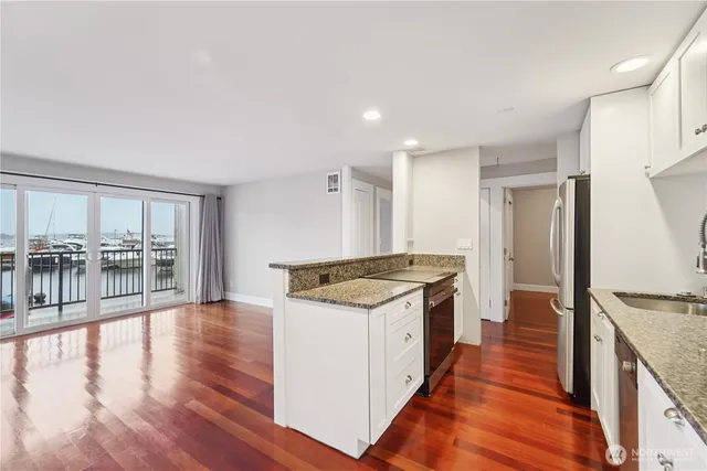 a large kitchen with stainless steel appliances granite countertop a stove and a wooden floors