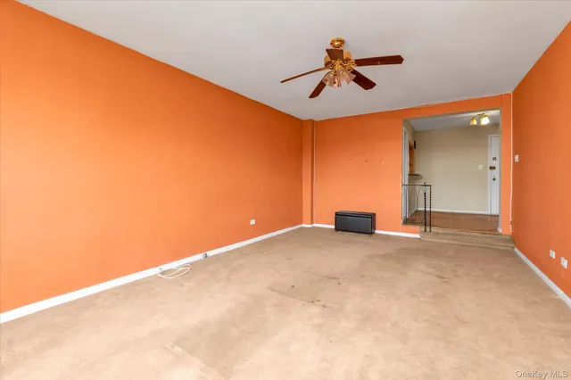 an empty room with chandelier fan and windows