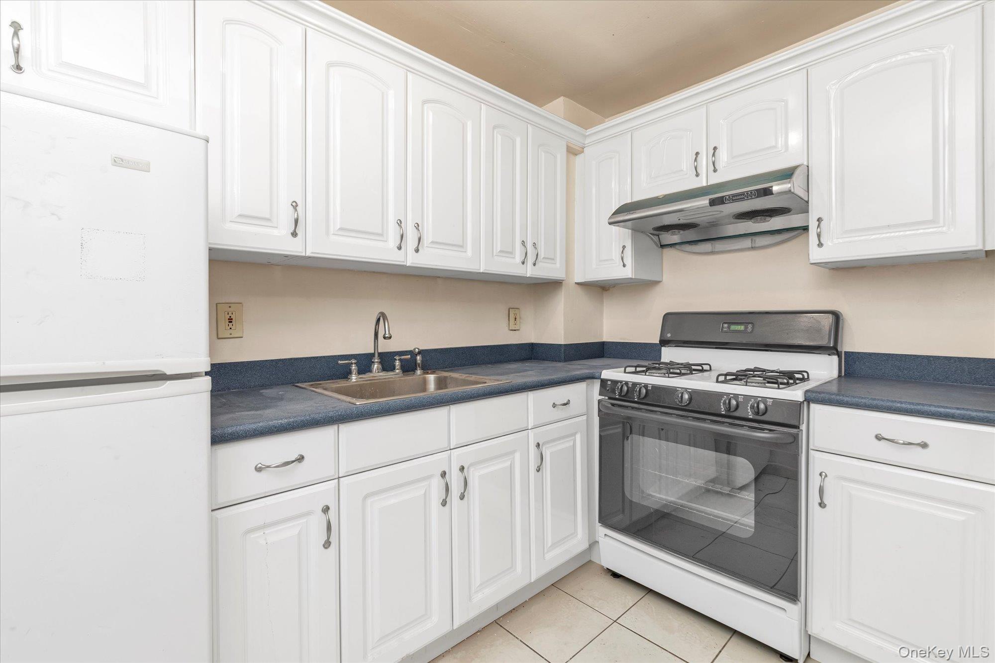 134-54 Maple Avenue, Unit 6M Queens, NY 11355 - Photo 7 of 15 a kitchen with granite countertop white cabinets and stainless steel appliances