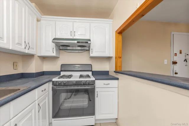 a kitchen with granite countertop white cabinets and white appliances