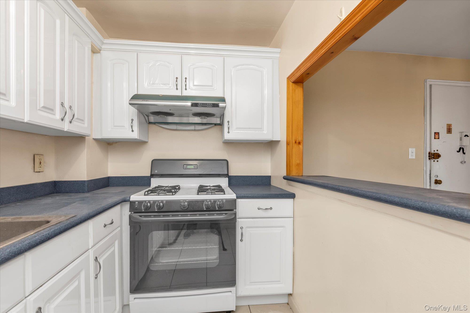134-54 Maple Avenue, Unit 6M Queens, NY 11355 - Photo 8 of 15 a kitchen with granite countertop white cabinets and white appliances