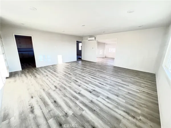 a view of an empty room with wooden floor and window