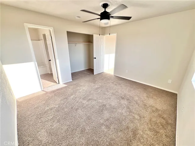 an empty room with a bathroom and a chandelier fan