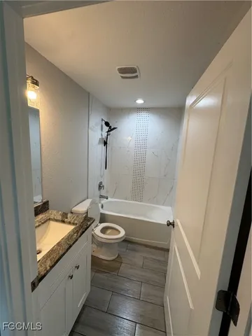 a bathroom with a granite countertop sink toilet and shower