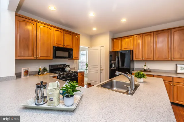 a kitchen with stainless steel appliances granite countertop a refrigerator a sink dishwasher a stove and a dining table with wooden floor