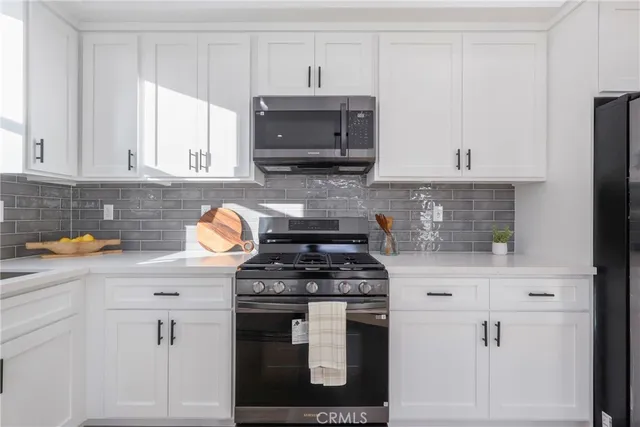 a kitchen with stainless steel appliances granite countertop a stove a sink and a microwave