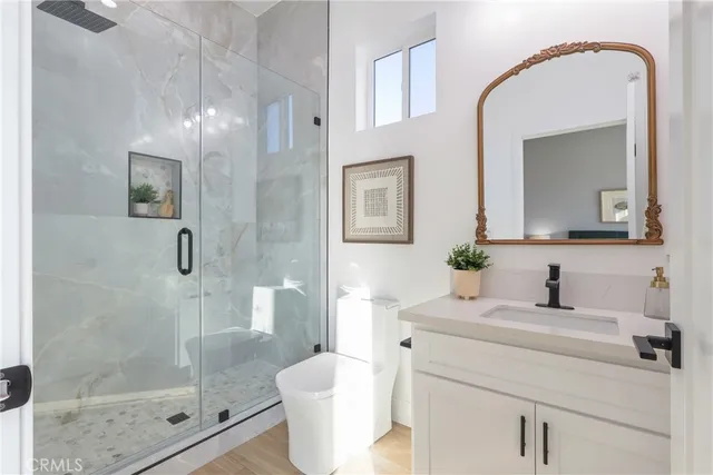 a bathroom with a granite countertop sink a toilet a mirror and shower