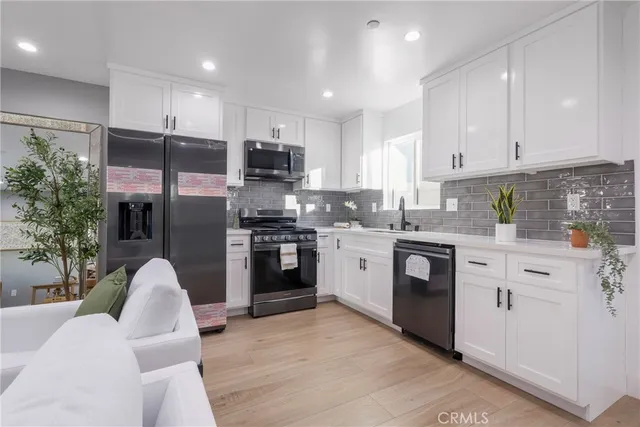 a kitchen with granite countertop a sink stainless steel appliances and white cabinets