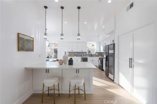 a kitchen with stainless steel appliances kitchen island granite countertop a table chairs refrigerator and microwave