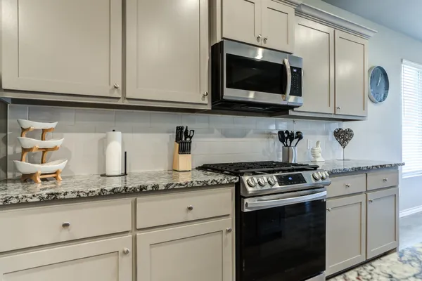 a kitchen with granite countertop white cabinets stainless steel appliances and a sink