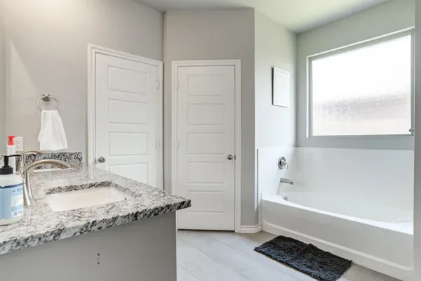 a bathroom with granite countertop bathtub sink and mirror