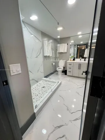 a kitchen with stainless steel appliances kitchen island granite countertop a dining table chairs and a refrigerator