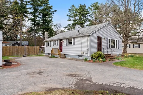 a view of a house with a yard and a large tree