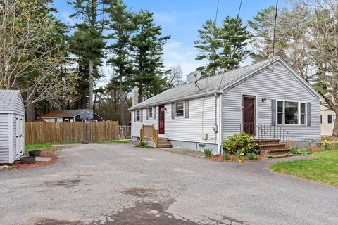 a view of a house with a yard and large trees