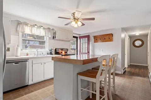 a kitchen with stainless steel appliances granite countertop a dining table chairs and a refrigerator