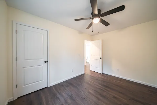 an empty room with wooden floor ceiling fan and windows