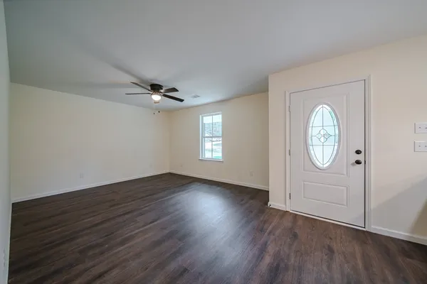 an empty room with wooden floor cabinet and door