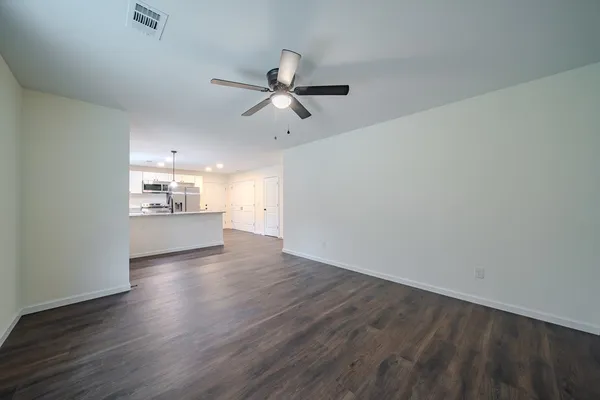 an empty room with wooden floor ceiling fan and windows