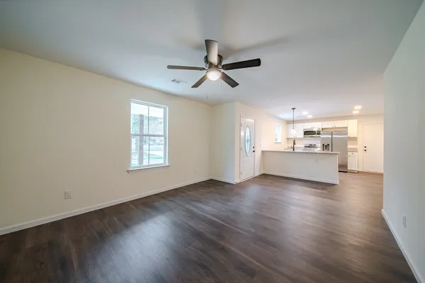 a view of an empty room with window and wooden floor