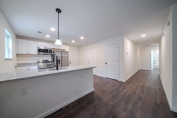 a large kitchen with stainless steel appliances a large counter top a sink a refrigerator and a window