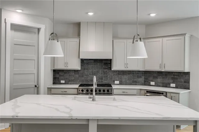 a large kitchen with stainless steel appliances granite countertop a stove a sink dishwasher and a refrigerator with wooden floor