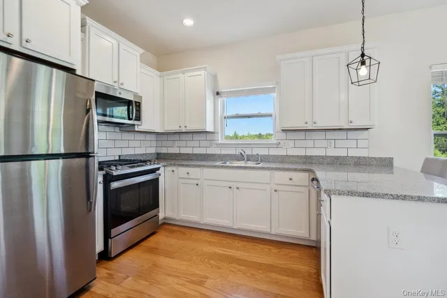a kitchen with stainless steel appliances granite countertop a sink a stove a refrigerator a microwave and cabinets