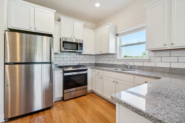 a kitchen with granite countertop white cabinets and stainless steel appliances