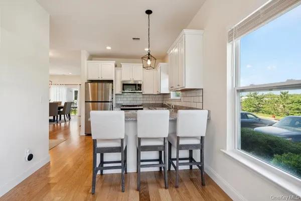 a kitchen with stainless steel appliances granite countertop a stove a refrigerator a oven a white table and chairs with wooden floor