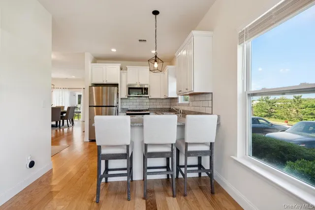 a kitchen with stainless steel appliances granite countertop a stove a refrigerator a oven a white table and chairs with wooden floor