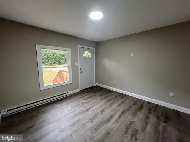 an empty room with wooden floor and windows