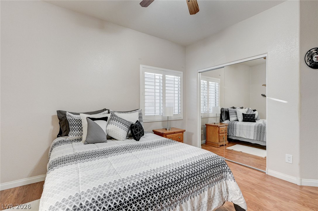 1604 Cattle Ranch Place Henderson, NV 89002 - Photo 51 of 99 Warm wood-toned flooring flows through this bright bedroom, featuring a large window with white louvered shutters.