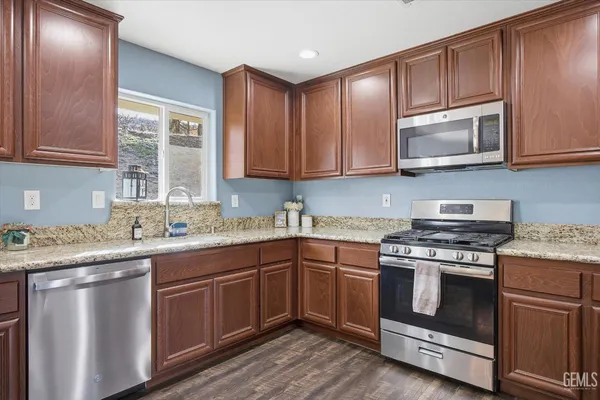 a kitchen with kitchen island wooden floors appliances and cabinets