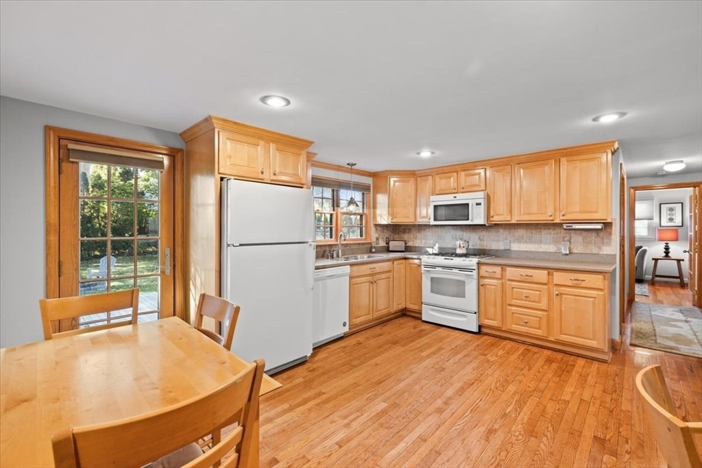 261 Emmett Street Fall River, MA 02721 - Photo 16 of 40 a kitchen with a refrigerator a stove top oven and a dining table with wooden floor